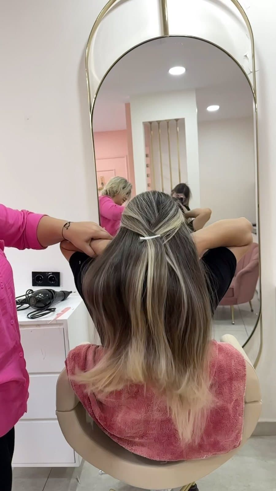 Pembe salonda, oval aynanın önünde saç yapımı